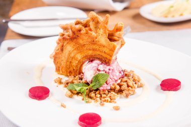 Lehçe-Litvanyaca geleneksel bir restoranda taze nane ile dekore edilmiş dondurma, kavrulmuş fındık ve ahududulu jöle ile pasta ('ağaç kek') - sekacz (Polonya) veya sakotis (Litvanyaca) tükürmek