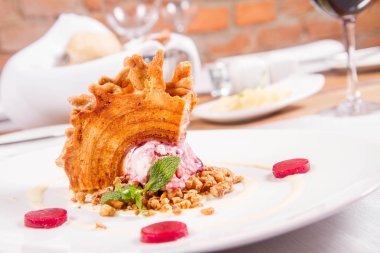 Lehçe-Litvanyaca geleneksel bir restoranda taze nane ile dekore edilmiş dondurma, kavrulmuş fındık ve ahududulu jöle ile pasta ('ağaç kek') - sekacz (Polonya) veya sakotis (Litvanyaca) tükürmek