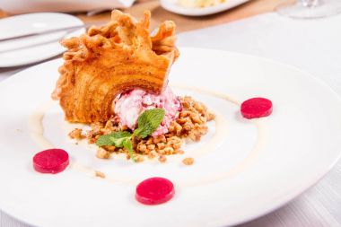 Lehçe-Litvanyaca geleneksel bir restoranda taze nane ile dekore edilmiş dondurma, kavrulmuş fındık ve ahududulu jöle ile pasta ('ağaç kek') - sekacz (Polonya) veya sakotis (Litvanyaca) tükürmek