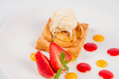 Bir çilek, meyve sosu ve bitki beyaz zemin üzerine elmalı pasta dondurma ile süslenmiş