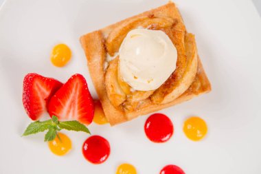 Bir çilek, meyve sosu ve bitki beyaz zemin üzerine elmalı pasta dondurma ile süslenmiş