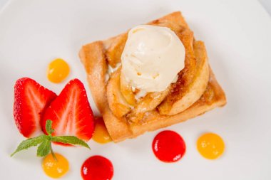 Bir çilek, meyve sosu ve bitki beyaz zemin üzerine elmalı pasta dondurma ile süslenmiş