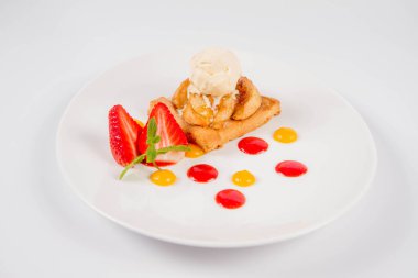 Bir çilek, meyve sosu ve bitki beyaz zemin üzerine elmalı pasta dondurma ile süslenmiş