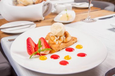 Elmalı turta dondurma çilek ile dekore edilmiş meyve sosu ve bitki bir restoranda servis