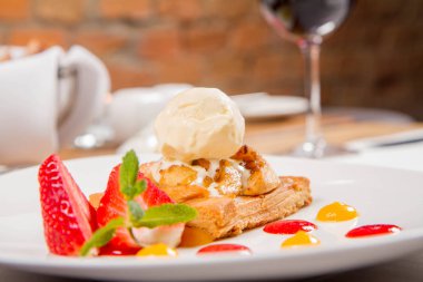 Elmalı turta dondurma çilek ile dekore edilmiş meyve sosu ve bitki bir restoranda servis