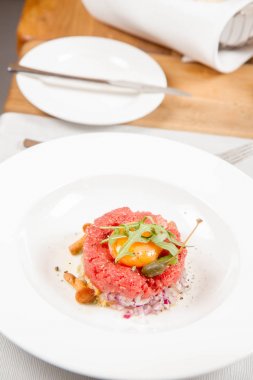 Steak tartare bir restoranda yumurta sarısı, soğan, Kapari, mantar ve roket salata ile servis