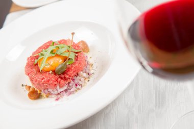 Steak tartare bir restoranda yumurta sarısı, soğan, Kapari, mantar ve roket salata ile servis