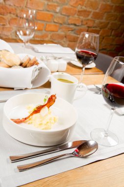 Bıldırcın yumurta, ekşi krema, patates püresi ve gevrek domuz pastırması ile kuzukulağı ve yeşil sebze çorbası Krem bir sürahi bir restoranda servis
