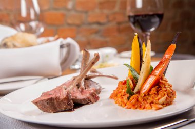 Kuzu pirzolası, kızarmış mercimek nane, kızartma sebze ve bir restoranda servis biberiye sos ile