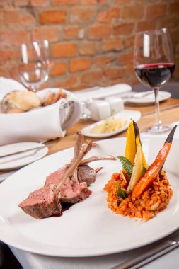 Kuzu pirzolası, kızarmış mercimek nane, kızartma sebze ve bir restoranda servis biberiye sos ile