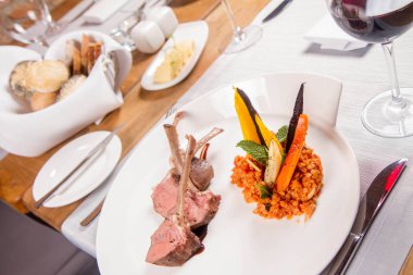 Kuzu pirzolası, kızarmış mercimek nane, kızartma sebze ve bir restoranda servis biberiye sos ile