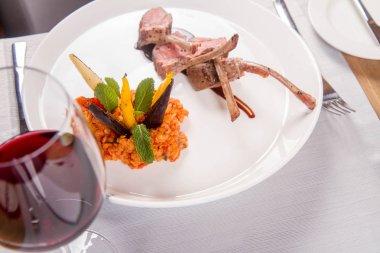 Kuzu pirzolası, kızarmış mercimek nane, kızartma sebze ve bir restoranda servis biberiye sos ile