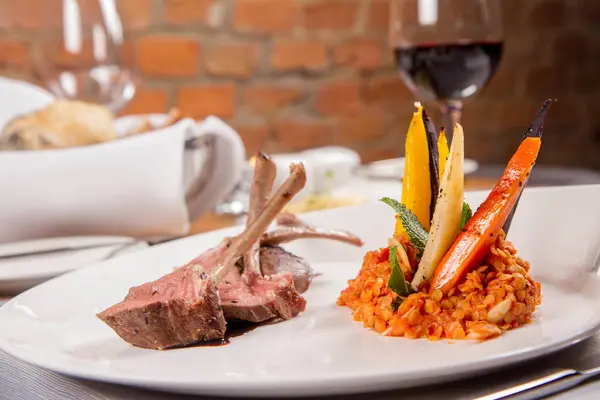 Kuzu pirzolası, kızarmış mercimek nane, kızartma sebze ve bir restoranda servis biberiye sos ile