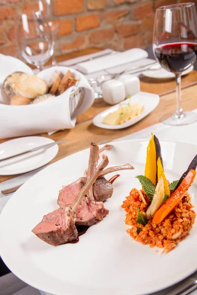 Kuzu pirzolası, kızarmış mercimek nane, kızartma sebze ve bir restoranda servis biberiye sos ile