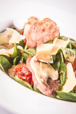 Bebek ıspanak, Kuru sosis, olgunlaştı peynir, kızarmış domates, kekik balsamik salata salata beyaz bir arka plan üzerinde