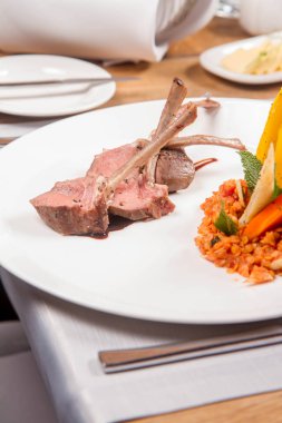 Kuzu pirzolası, kızarmış mercimek nane, kızartma sebze ve bir restoranda servis biberiye sos ile