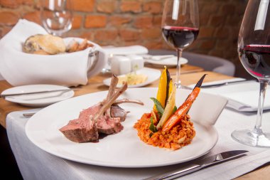 Kuzu pirzolası, kızarmış mercimek nane, kızartma sebze ve bir restoranda servis biberiye sos ile