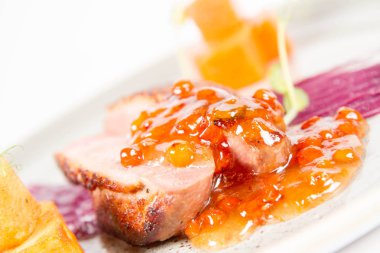 Beyaz bir backgorund üzerinde bir tabakta kavrulmuş patates, üvez ve bal sosu ördek göğsü, kırmızı lahana ile elma, kızartma