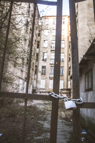 Abandoned tenant house, with a gate closed with a padlock in the foreground, in Warsaw, Poland