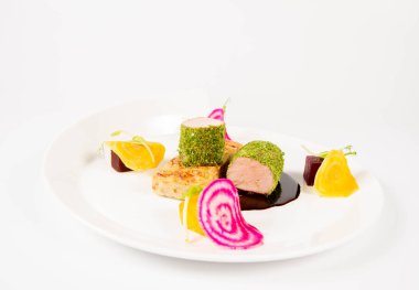 Beyaz zemin üzerinde bir plaka üzerinde Marine beetroots ve yeşil biber soslu domuz eti bonfile gevrek patates ekmek ile kızartma