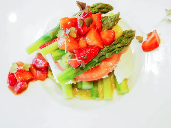 Asparagus and strawberries salad with tomato, and cheese