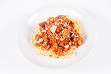 Beyaz arka planda parmesanlı spagetti bolonez serpilmiş.