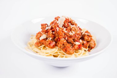 Beyaz arka planda parmesanlı spagetti bolonez serpilmiş.