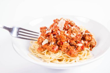 Beyaz arka planda bir tabağa parmesan serpiştirilmiş spagetti soslu ve çatalla yenmiş.