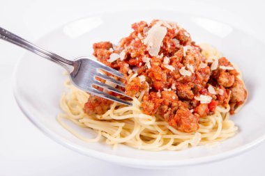 Beyaz arka planda bir tabağa parmesan serpiştirilmiş spagetti soslu ve çatalla yenmiş.
