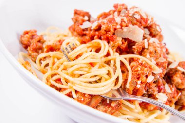 Beyaz arka planda çatalla yenen spagetti bolonezi.