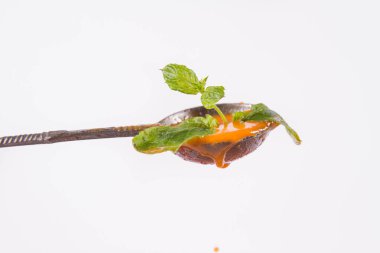 Antika bir kaşıkta beyaz arka planda taze nane ile süslenmiş gazpacho çorbası.