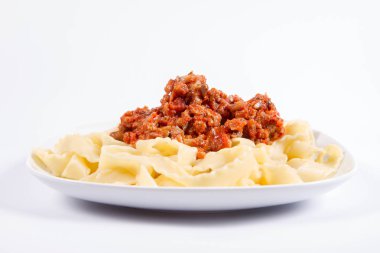 Beyaz arka planda bir tabakta bolonez soslu reginette makarna.