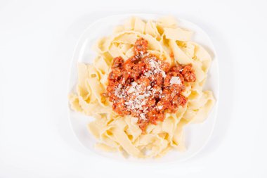 Beyaz arka planda parmesanla süslenmiş bolonez soslu reginette makarna.