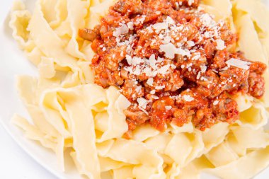 Beyaz arka planda parmesanla süslenmiş bolonez soslu reginette makarna.