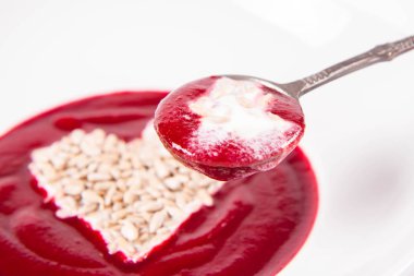 Yoğurttan yapılmış bir kalple süslenmiş pancar kremalı çorba ve ayçiçeği tohumları eski bir kaşıkla yenir.