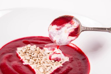 Yoğurttan yapılmış bir kalple süslenmiş pancar kremalı çorba ve ayçiçeği tohumları eski bir kaşıkla yenir.