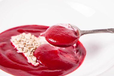 Yoğurttan yapılmış bir kalple süslenmiş pancar kremalı çorba ve ayçiçeği tohumları eski bir kaşıkla yenir.