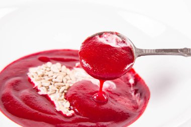 Yoğurttan yapılmış bir kalple süslenmiş pancar kremalı çorba ve ayçiçeği tohumları eski bir kaşıkla yenir.