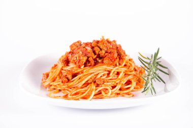 Biberiye dalıyla süslenmiş bir tabakta spagetti bolonez.