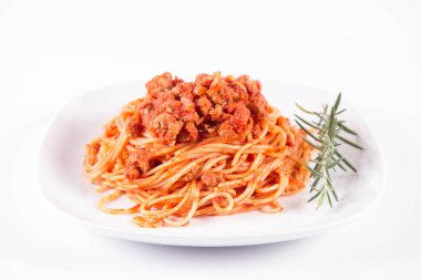 Biberiye dalıyla süslenmiş bir tabakta spagetti bolonez.