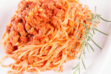 Biberiye dalıyla süslenmiş bir tabakta spagetti bolonez.