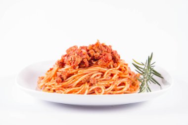 Biberiye dalıyla süslenmiş bir tabakta spagetti bolonez.