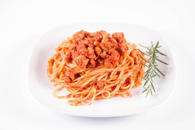 Biberiye dalıyla süslenmiş bir tabakta spagetti bolonez.