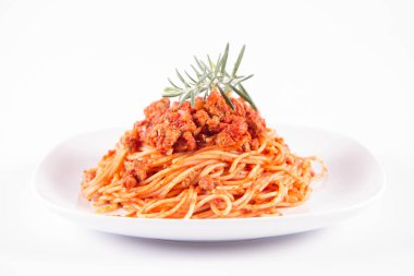 Biberiye dalıyla süslenmiş bir tabakta spagetti bolonez.