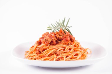 Biberiye dalıyla süslenmiş bir tabakta spagetti bolonez.