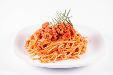 Biberiye dalıyla süslenmiş bir tabakta spagetti bolonez.