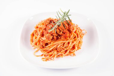 Biberiye dalıyla süslenmiş bir tabakta spagetti bolonez.