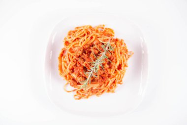 Biberiye dalıyla süslenmiş bir tabakta spagetti bolonez.