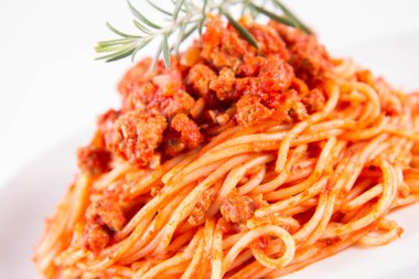 Biberiye dalıyla süslenmiş bir tabakta spagetti bolonez.