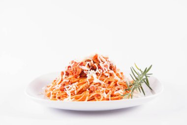 Biberiye dalıyla süslenmiş ve üzerine peynir serpiştirilmiş bir tabak spagetti bolonez.